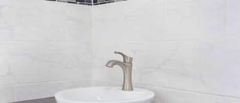 A bathroom with a white sink, a modern faucet, and a dark countertop.