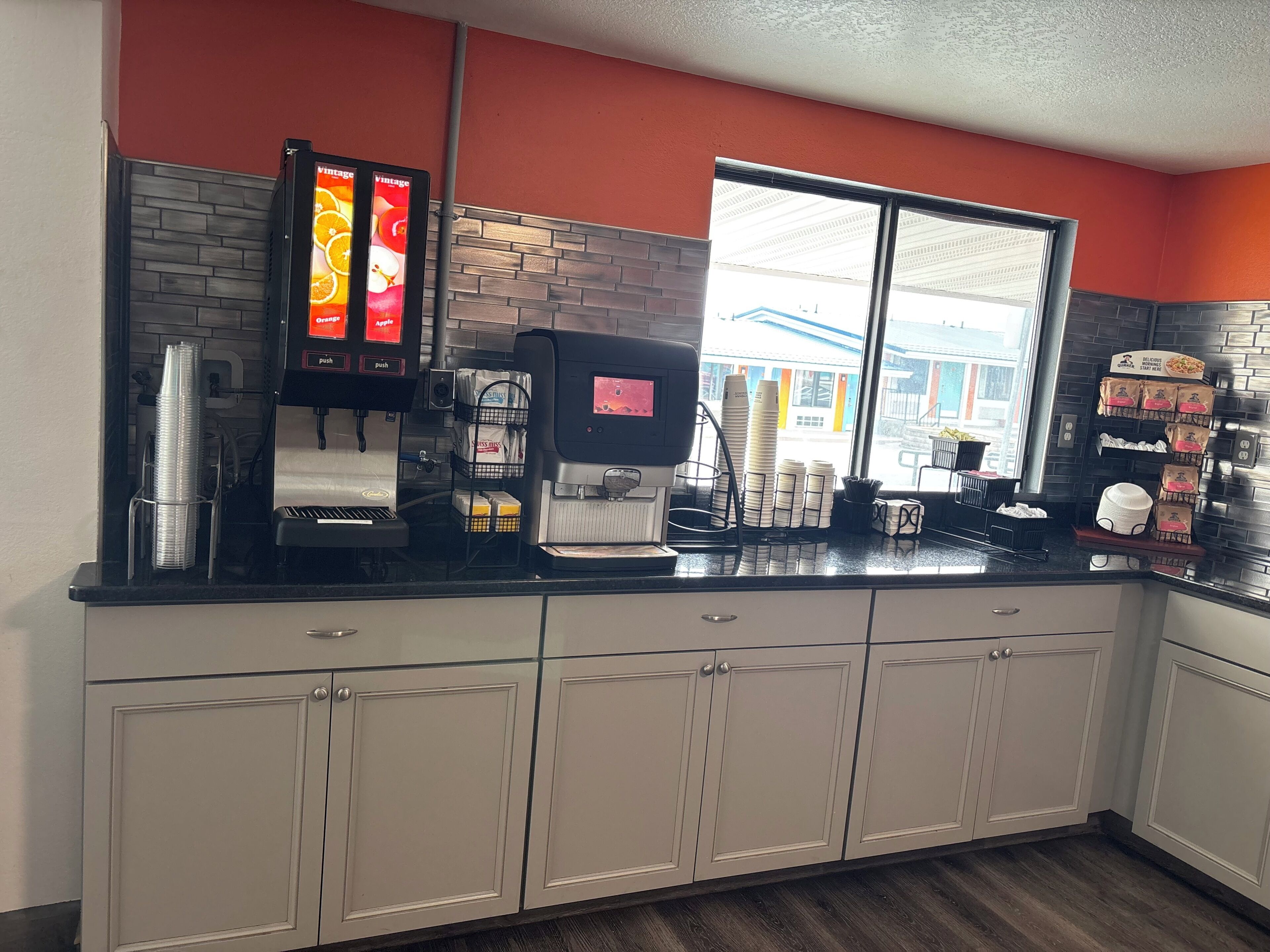 A coffee shop interior with a coffee machine, a menu board, and a window with a view of the outside.