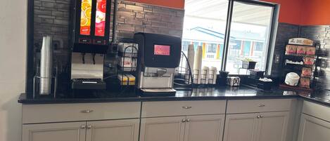 A coffee shop interior with a coffee machine, a menu board, and a window with a view of the outside.