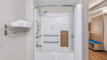 A bathroom with a bathtub, a shower, and a toilet. There are grab bars and a towel rack.