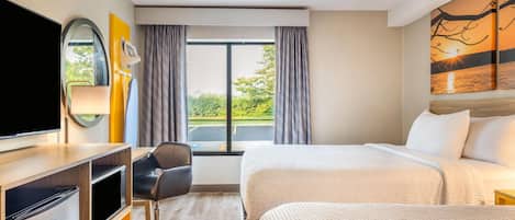 Habitación de hotel con cama, escritorio con televisor, silla y ventana con cortinas.