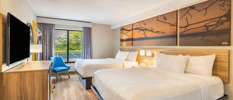 A hotel room with two beds, a TV, a desk, a chair, and a painting on the wall.
