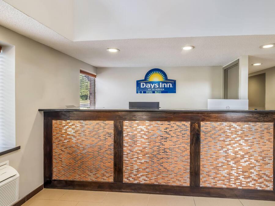 Una recepción con el letrero de Days Inn, una computadora y una ventana con persianas.