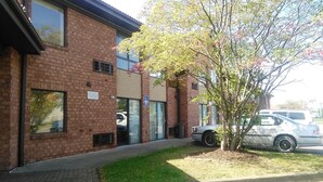 A brick building with a parking lot, a tree, and a parked car. - Americas Best Value Inn Horseheads (Horseheads)