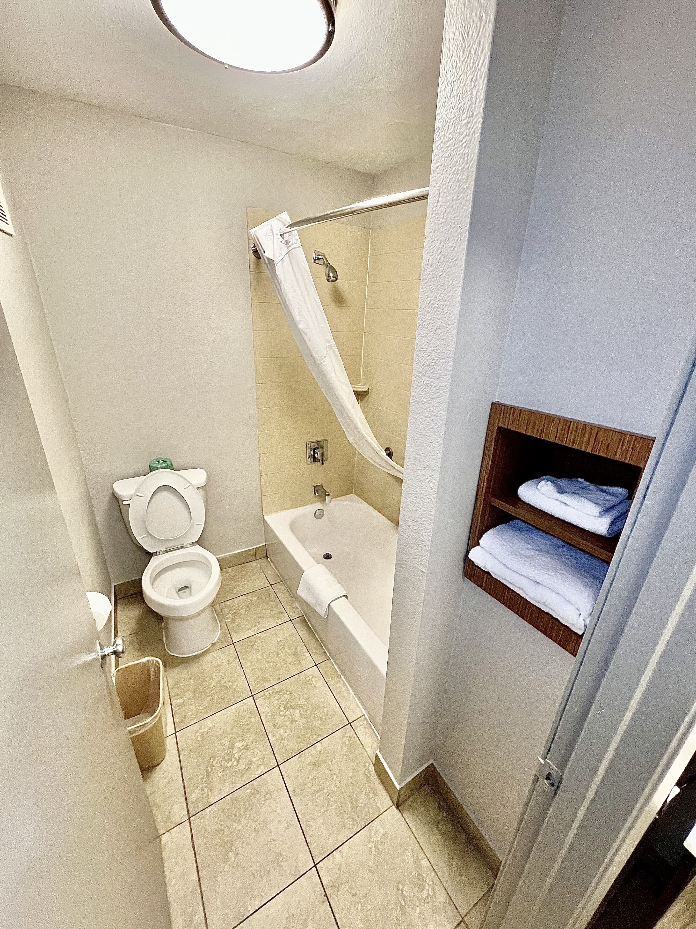 A bathroom with a toilet, bathtub, and a shower curtain.