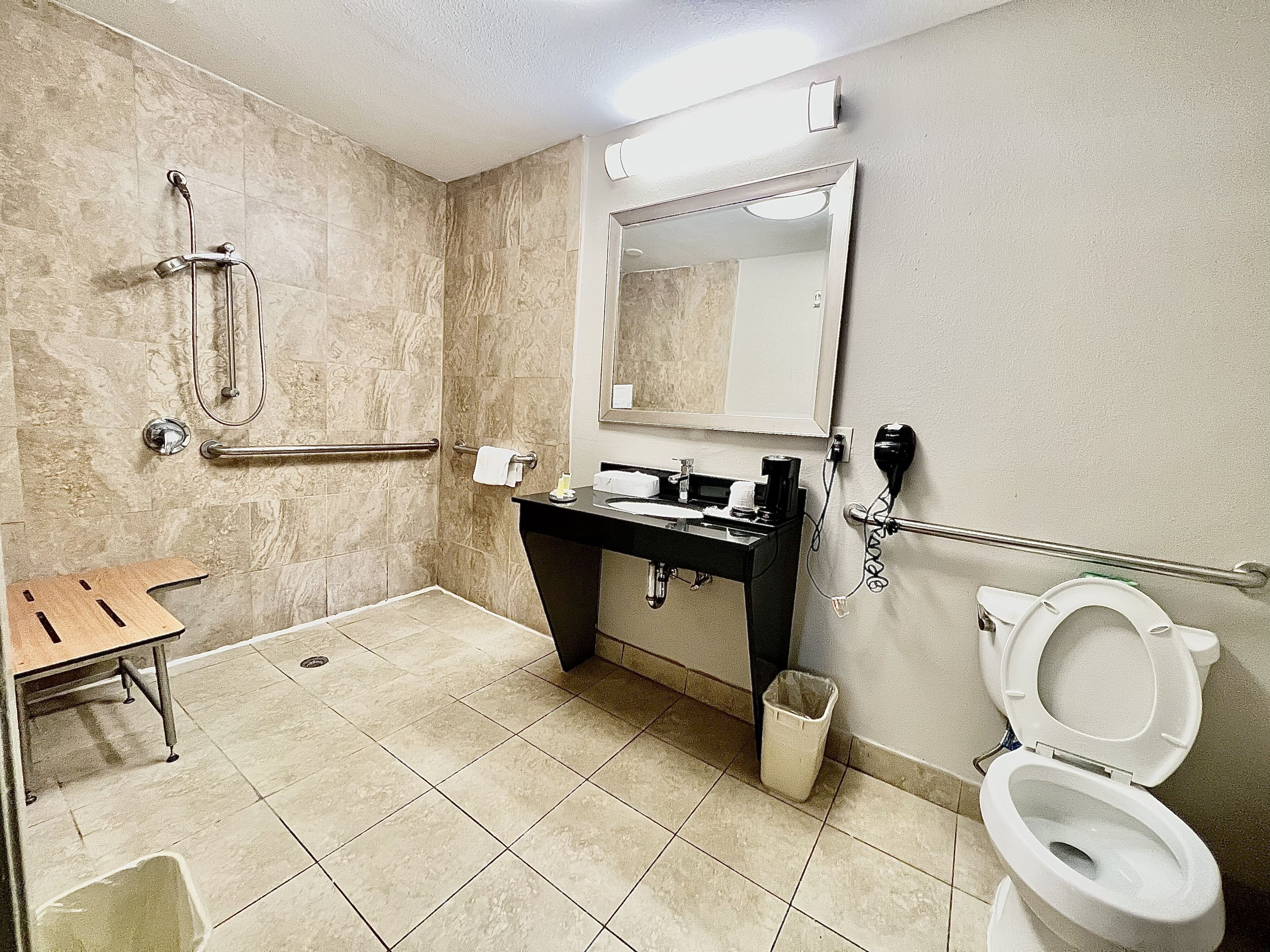 A bathroom with a shower, toilet, sink, and a mirror.