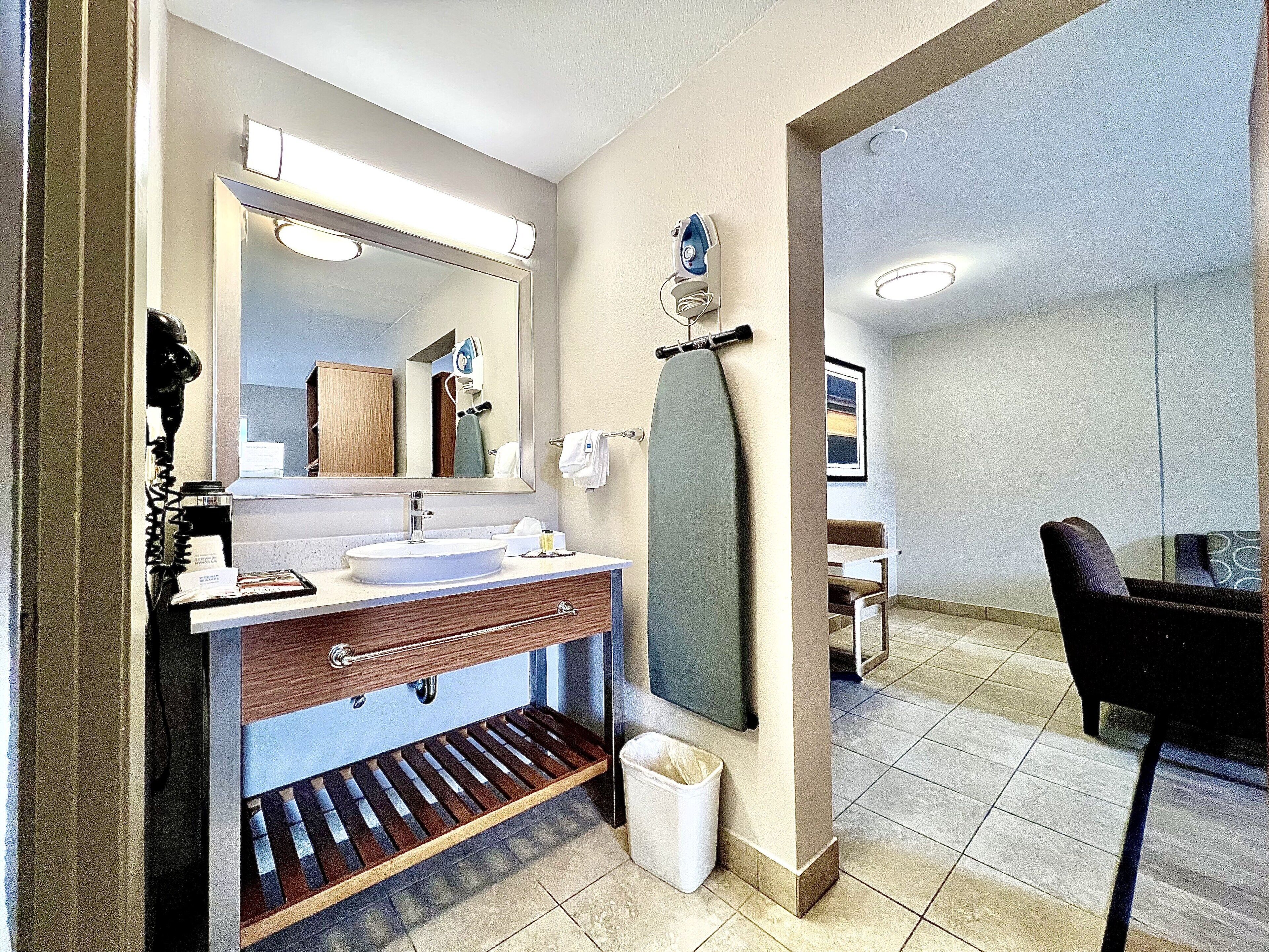 A modern bathroom with a large mirror, a sink, and a towel rack.