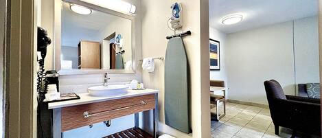 A modern bathroom with a large mirror, a sink, and a towel rack.
