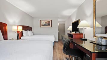 A hotel room with two beds, a desk with a chair, a television, and a mirror.