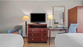 A hotel room with two beds, a TV, a dresser, a desk, a chair, and a mirror.