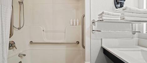 Un baño con bañera, ducha, toallero y dispensador de jabón.