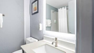 Un baño con un lavabo blanco, un espejo, un inodoro y una cortina de ducha.
