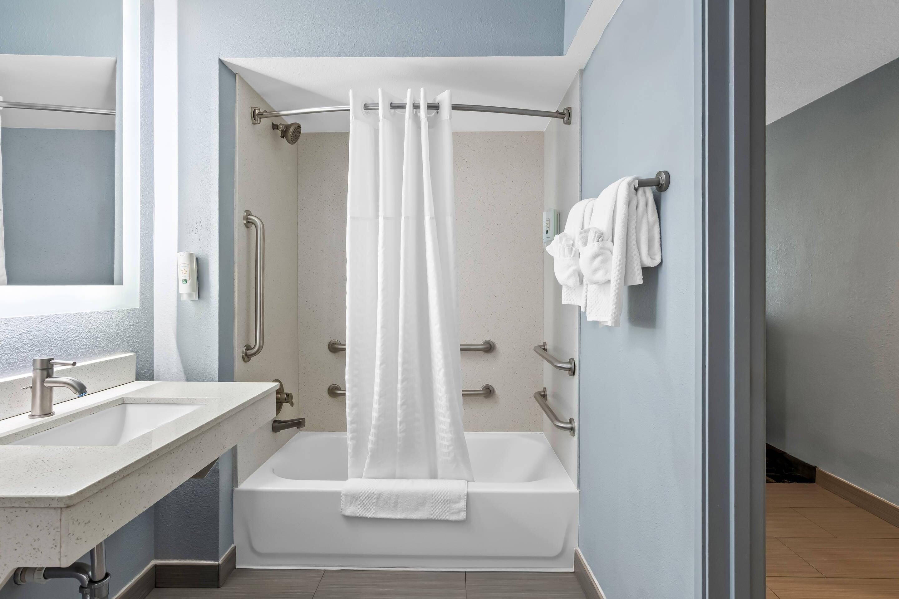 Un baño con bañera, ducha, lavabo y espejo.