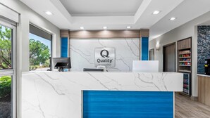 Ein Hotelrezeptionstresen mit Marmorplatte, blauen Akzenten und einem Schild mit der Aufschrift 'Quality by Choice Hotels'.