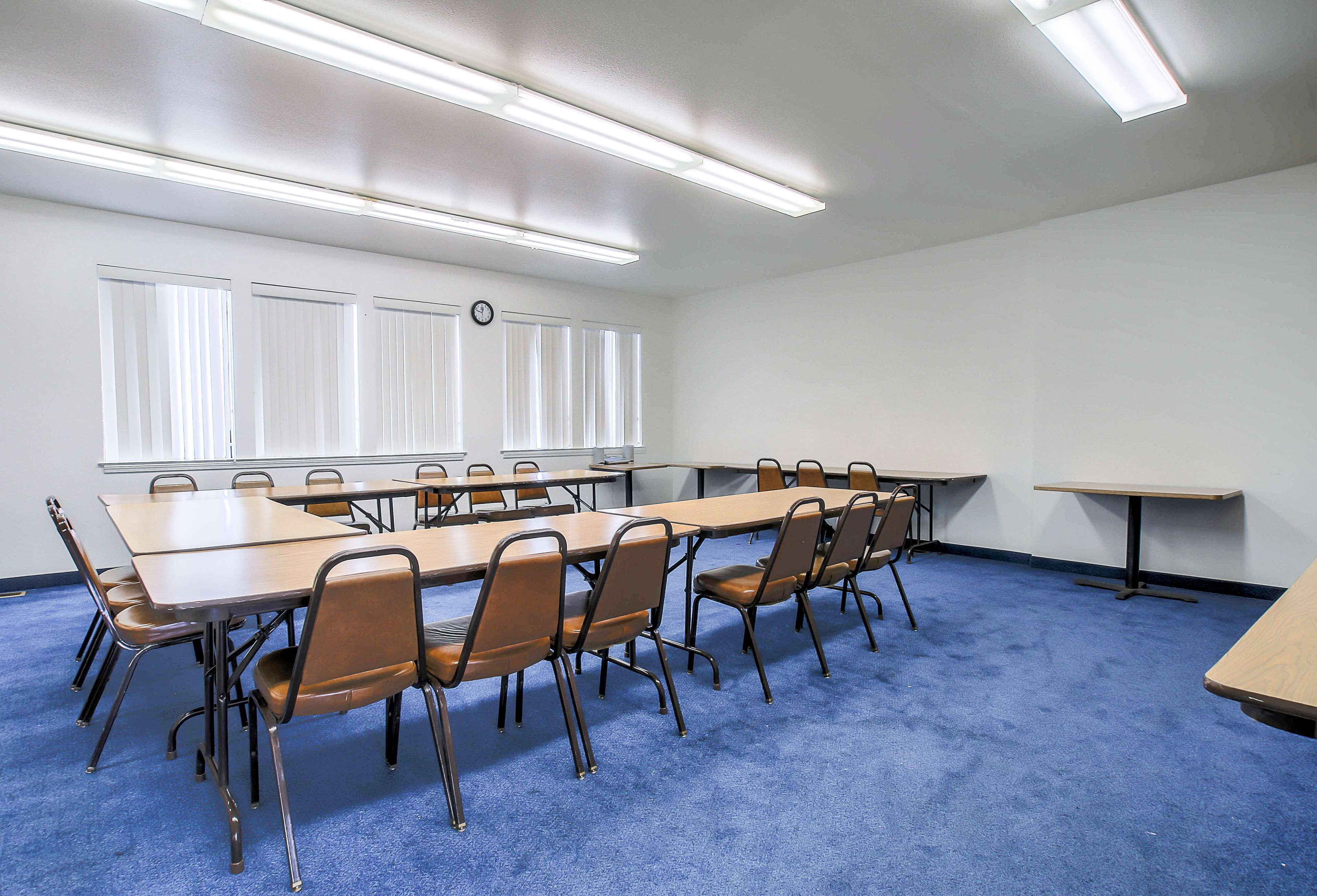 Una sala conferenze con un lungo tavolo, sedie e un orologio appeso al muro.