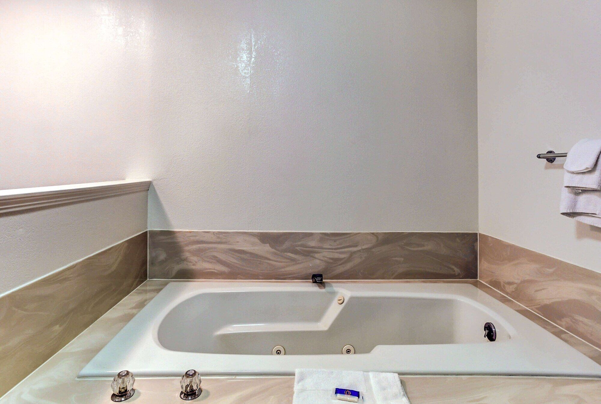Un bagno moderno con una vasca freestanding, un portasciugamani e una parete rivestita in marmo.