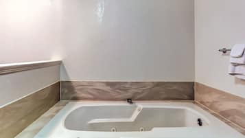 Un bagno moderno con una vasca freestanding, un portasciugamani e una parete rivestita in marmo.