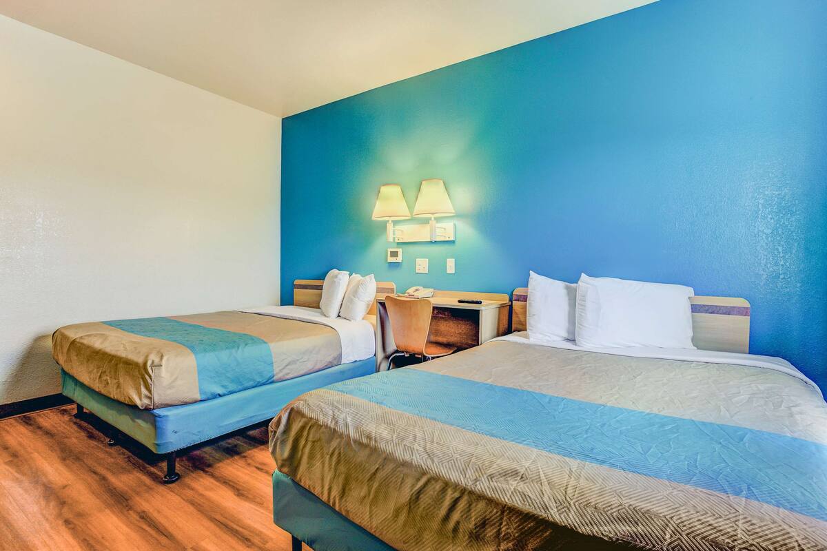A hotel room with two beds, a desk, and a chair.