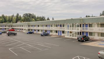 Un motel con varias habitaciones, un estacionamiento y vistas a árboles.