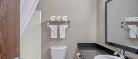 Un baño con inodoro, lavamanos y barra para toallas.