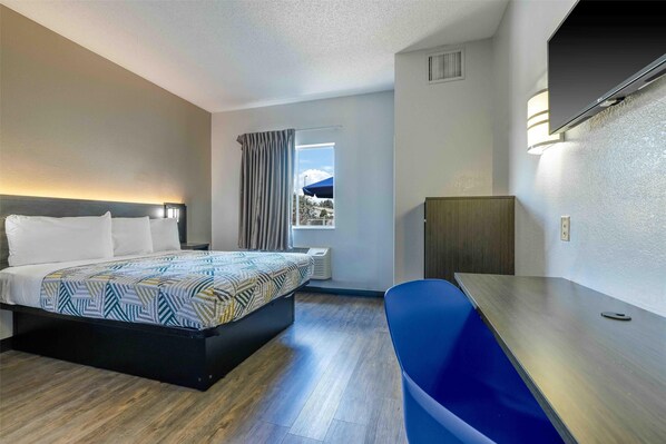 A hotel room with a bed, a desk, a chair, a window with curtains, and a view of the outside. - Motel 6 Albuquerque, NM - North (Albuquerque)