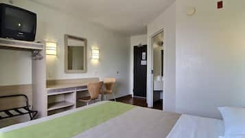 A hotel room with a bed, a desk, a chair, a television, and a mirror.