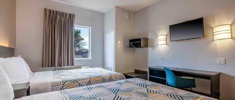 Habitación de hotel con dos camas, un escritorio, una silla, un televisor montado en la pared y una ventana con cortinas.