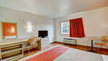 A modern hotel room with a bed, desk, chair, television, and a window with curtains.