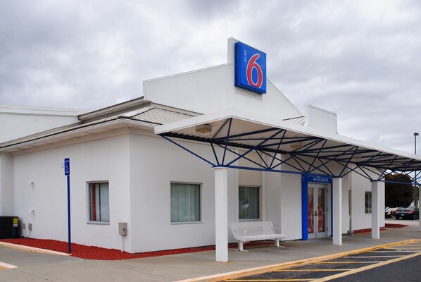 A motel with a blue sign, a covered entrance, and a white exterior. - Motel 6 Seekonk, MA - Providence East (Seekonk)