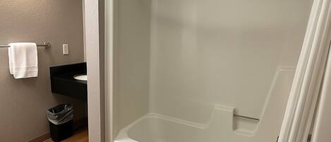 A modern bathroom with a glass-enclosed shower, a white bathtub, and a black sink.