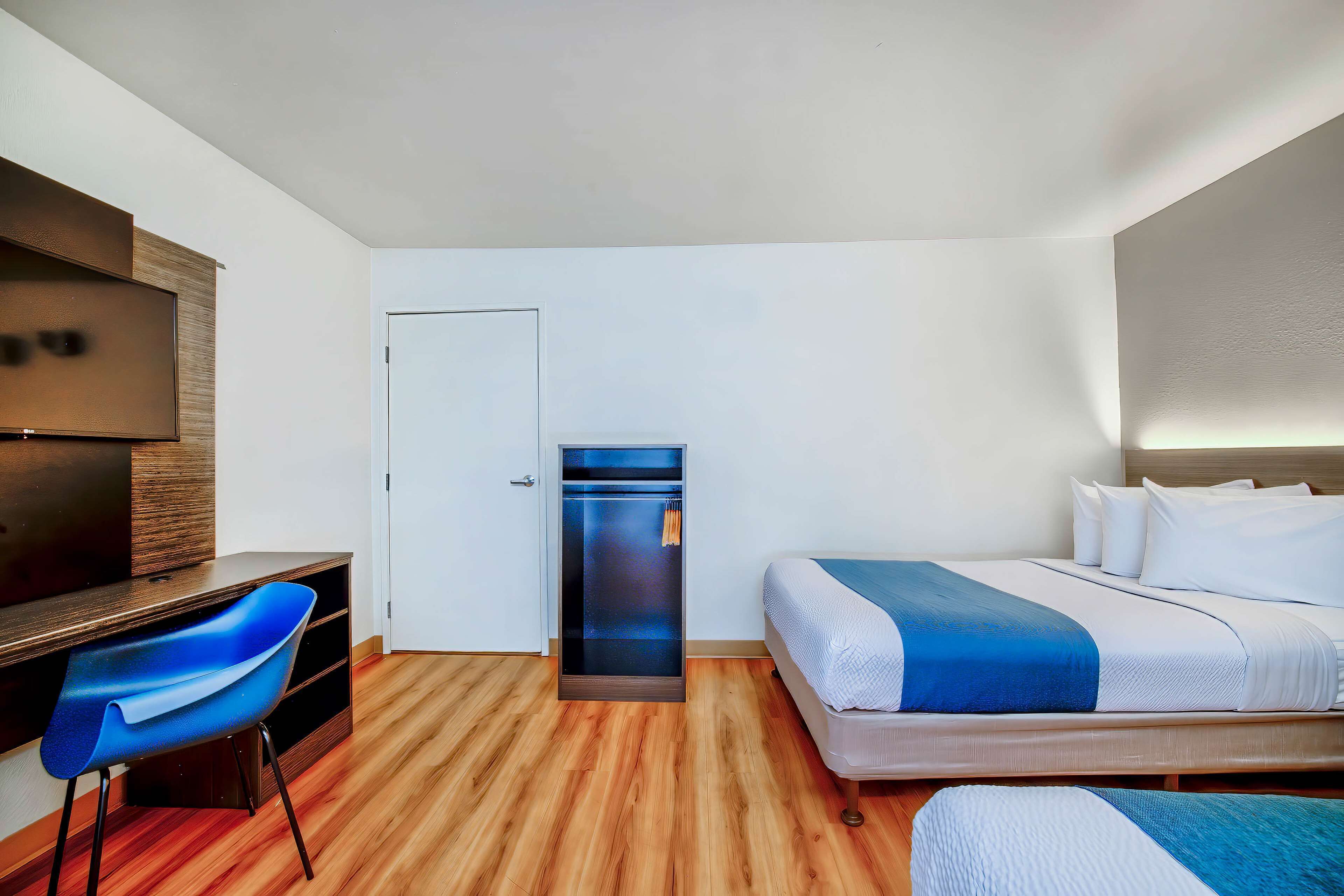Ein Hotelzimmer mit einem Bett, einem Schreibtisch, einem Stuhl, einem Kleiderschrank und einem Fernseher.