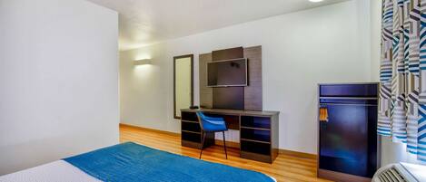 A hotel room with a bed, a desk with a chair, a television, and a wardrobe.