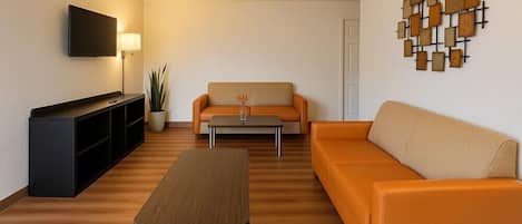 Ein modernes Wohnzimmer mit einer Couch, einem Couchtisch, einem Fernseher und einer Wanddekoration.