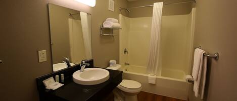 A bathroom with a sink, mirror, toilet, and shower.