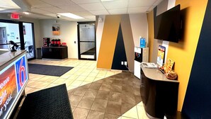 A reception area with a counter, a water dispenser, a television, and a seating area with a black chair.