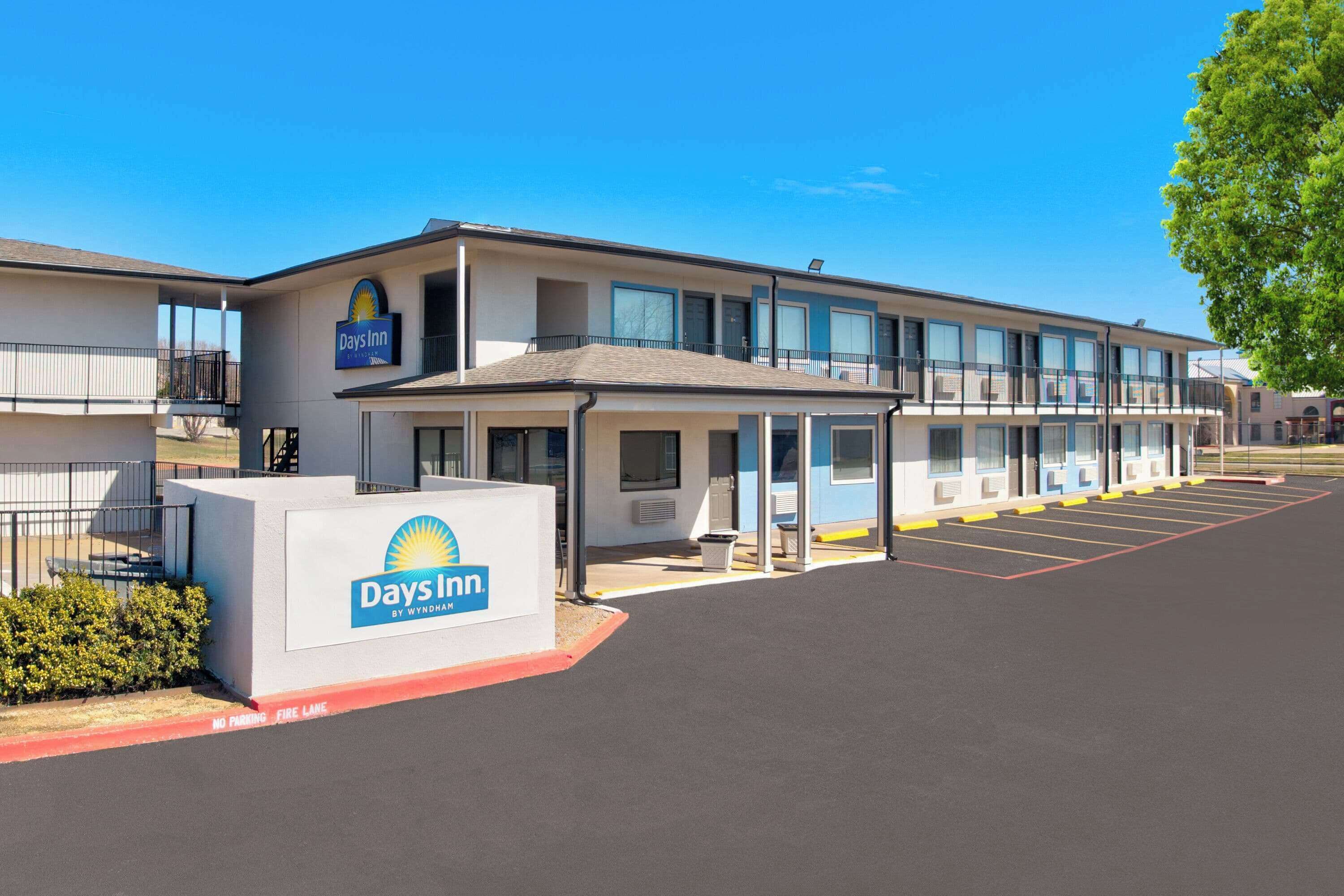 Un Days Inn by Wyndham con ingresso coperto, un parcheggio e cielo sereno.
