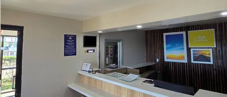 A reception desk with a wooden panel design, a digital screen, and a welcome sign.