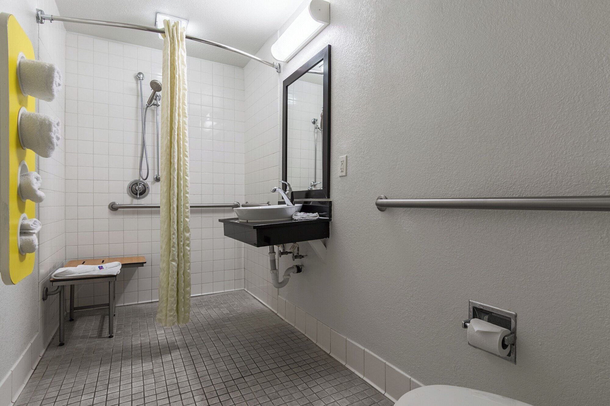 Une salle de bain équipée d’une douche, d’un lavabo, d’un miroir, de toilettes et d’un porte-serviettes.