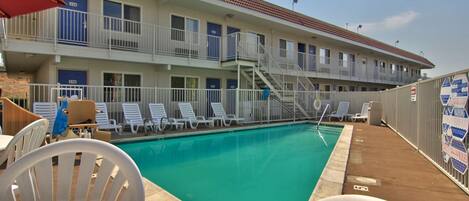 A hotel with a swimming pool, multiple balconies, and outdoor seating.