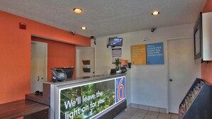 A reception desk with a monitor displaying a message, a telephone, and a sign with motivational quotes.