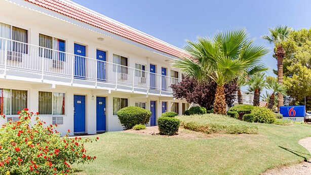 A motel with a two-story structure, multiple rooms with blue doors, and a well-maintained lawn with various plants. - Motel 6 Tempe, AZ - Scottsdale South (Tempe)