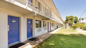 A row of blue doors with numbers 115 and 114, indicating a hotel or apartment building with a uniform facade and a small front yard.