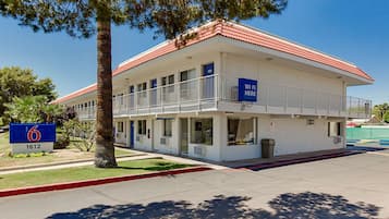 A two-story motel with a red-tiled roof, a balcony on the second floor, and a sign indicating WiFi availability.