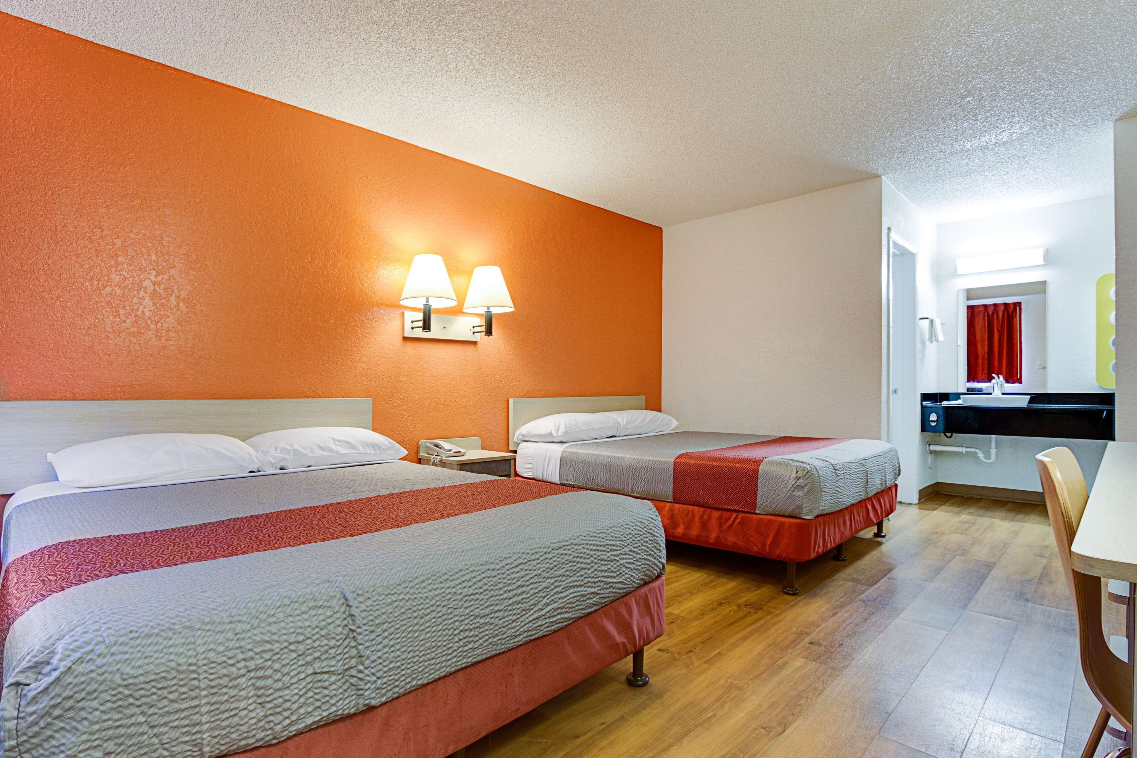 Une chambre d’hôtel avec deux lits, un petit bureau et une salle de bain visible à travers une porte ouverte.
