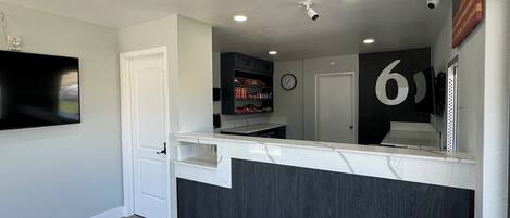 A modern kitchen with a marble countertop, dark wood paneling, and recessed ceiling lights.
