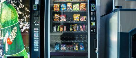 Un distributeur automatique proposant une variété de collations et de boissons gazeuses.