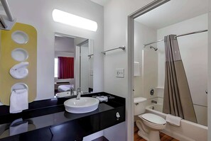 A modern bathroom with a black sink, white toilet, and a glass-enclosed shower area. - Motel 6 Modesto CA (Modesto)