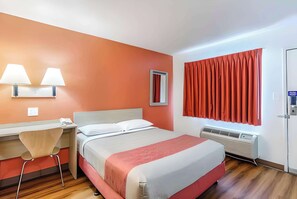 Relax in this stylish room featuring a comfortable bed, a desk for work, and a wall-mounted lamp.