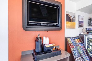 A coffee station with a coffee machine, cups, and a display of coffee pods. - Motel 6 Modesto CA (Modesto)