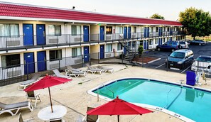 A motel with a swimming pool, multiple balconies, and a parking area.